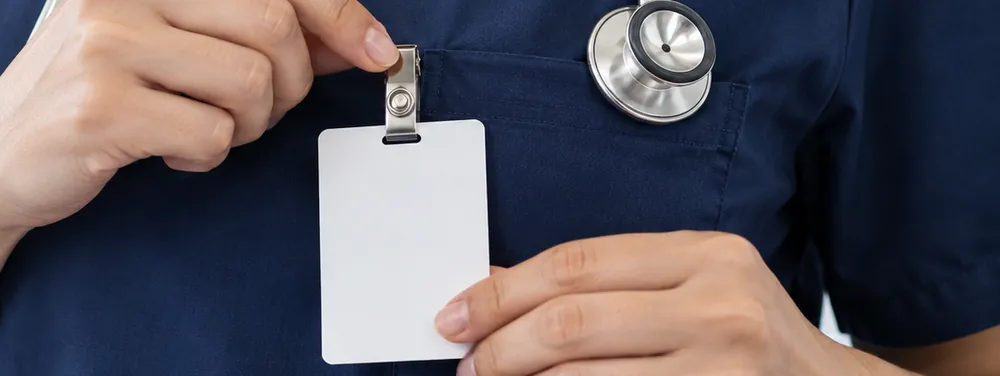 Nurse in navy scrubs clipping on a new hospital ID badge